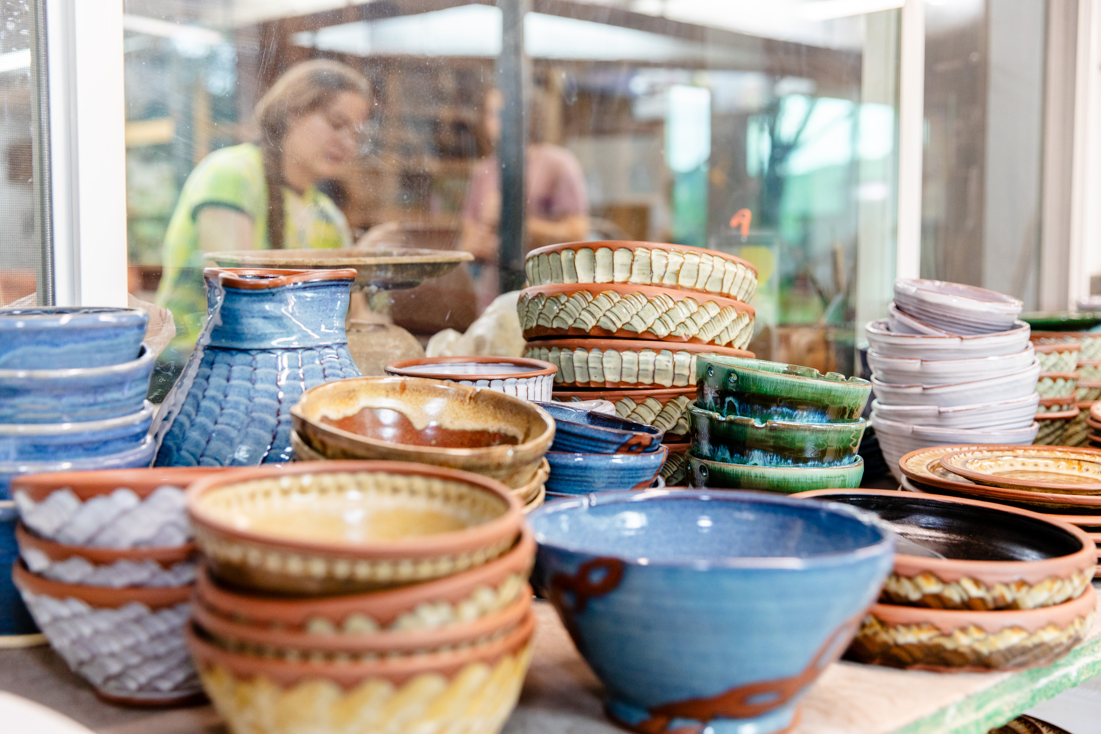 Yellow, blue, and natural clay bowls sit on a table in the Page Pottery studio.