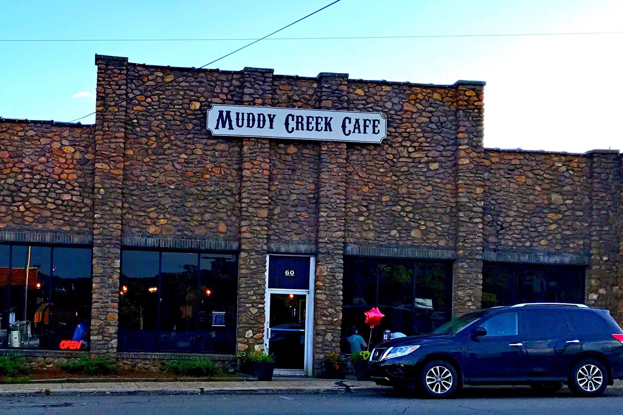 Muddy Creek Music Hall has a rock facade with several large windows looking out to the street.