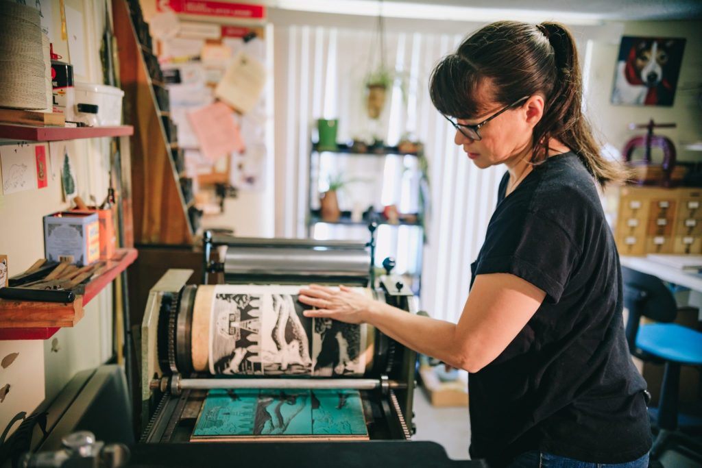 Jessica White creates a print on a printing press.