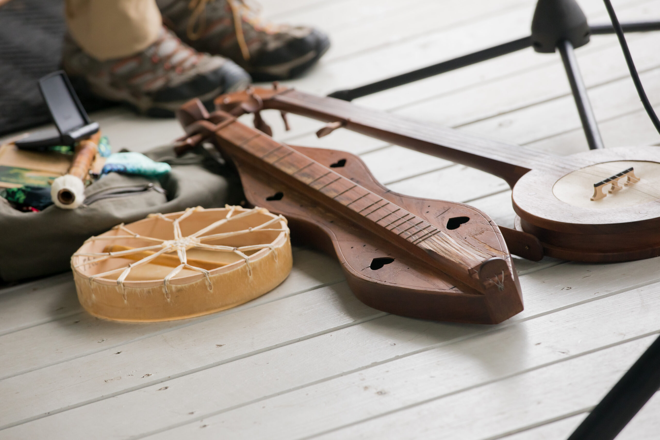 Instruments sit on a wooden porch, including a fiddle and and two folk instruments.
