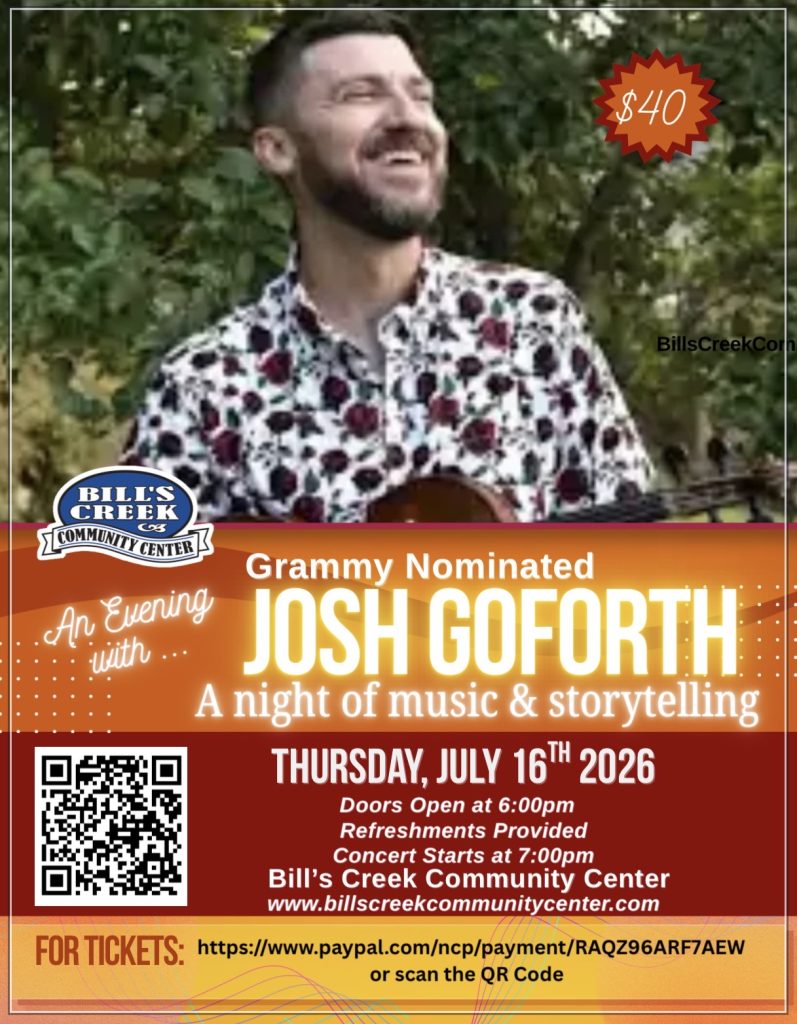 Josh Goforth stands smiling in front of green foliage.