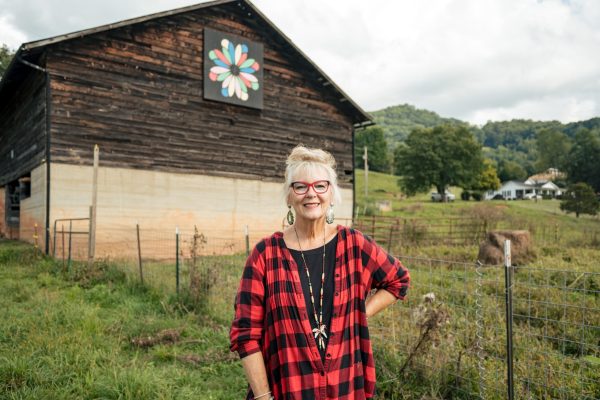 Lillian Howell Rumsey stands with the Flower Petals Block at The Barn Quilt Farmhouse on Howell Farm in Jonathan Creek Valley, Waynesville.