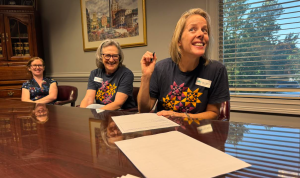 Haywood County Arts Council staff signs paperwork for the art council's new building.